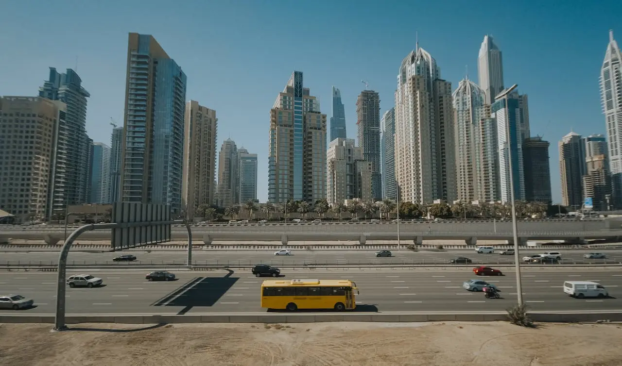 Panoramic view of Dubai Marina skyscrapers with vehicles on a sunny highway.
